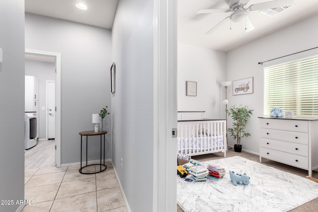 bedroom featuring washer / clothes dryer, a crib, and light tile patterned flooring