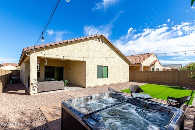 rear view of house featuring cooling unit, a patio area, and a hot tub