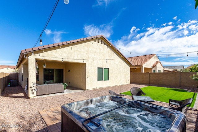 rear view of house featuring cooling unit, an outdoor living space, a hot tub, and a patio area