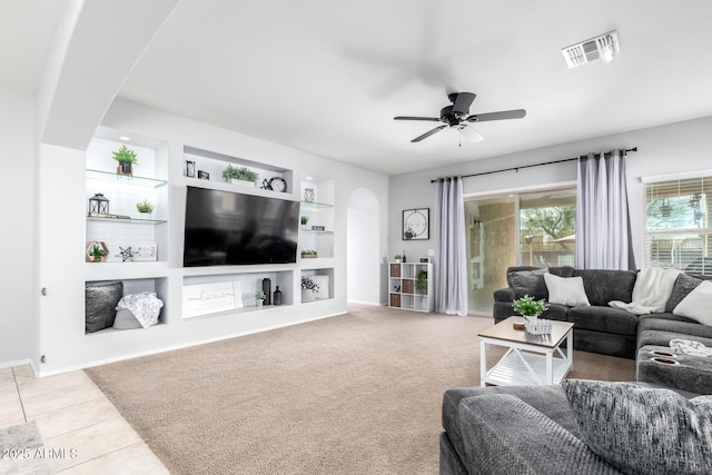 living room featuring ceiling fan, light carpet, and built in features