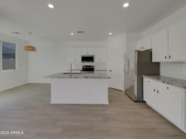 kitchen featuring visible vents, a sink, light stone counters, stainless steel appliances, and white cabinets