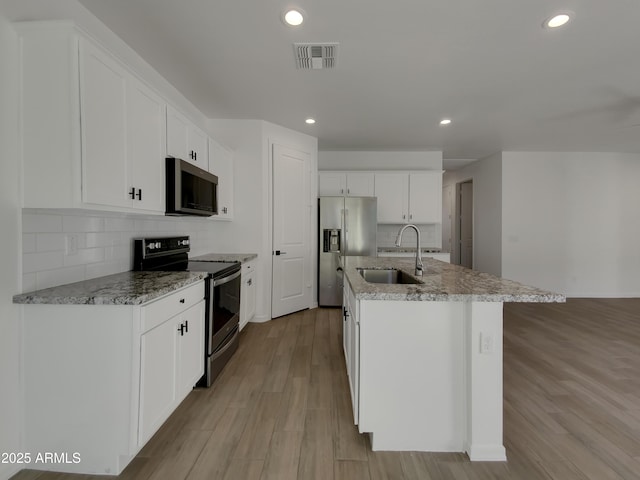 kitchen with visible vents, a sink, stainless steel appliances, light wood-style floors, and white cabinetry