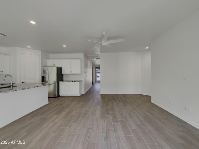 unfurnished living room featuring visible vents, recessed lighting, light wood-style flooring, a ceiling fan, and a sink