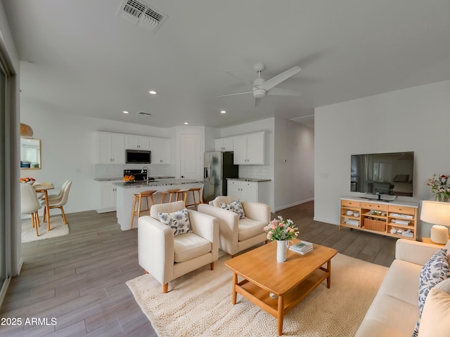 living area with light wood-style flooring, recessed lighting, visible vents, and ceiling fan