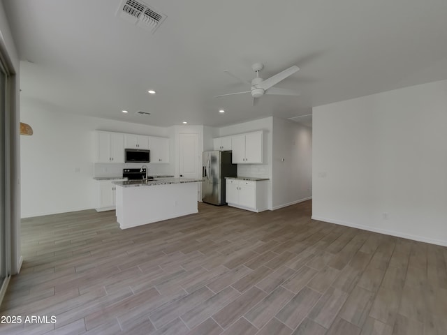 kitchen featuring visible vents, light stone counters, open floor plan, stainless steel fridge with ice dispenser, and ceiling fan