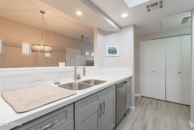 kitchen with hanging light fixtures, sink, gray cabinetry, stainless steel dishwasher, and light hardwood / wood-style flooring