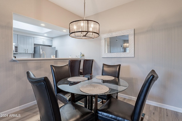 dining space with light hardwood / wood-style floors and a chandelier