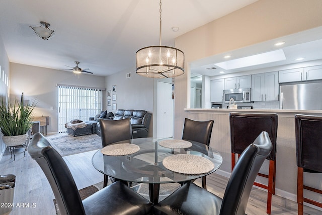 dining space featuring ceiling fan with notable chandelier and light hardwood / wood-style flooring