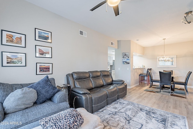 living room with light wood-type flooring and ceiling fan with notable chandelier