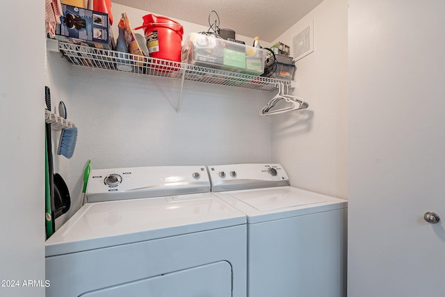 clothes washing area with a textured ceiling and washer and dryer