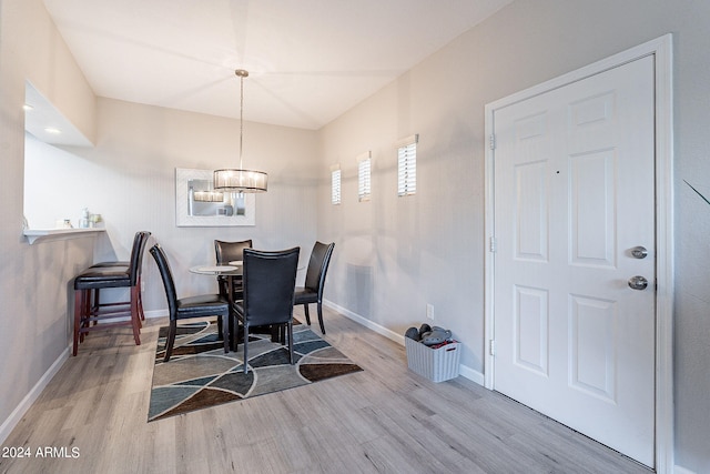 dining space with light hardwood / wood-style flooring and a chandelier