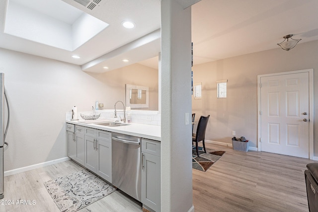 kitchen with light wood-type flooring, gray cabinets, dishwasher, and sink