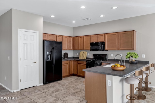 kitchen with dark countertops, brown cabinets, a peninsula, and black appliances