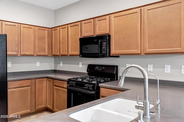 kitchen with dark countertops, black appliances, and a sink