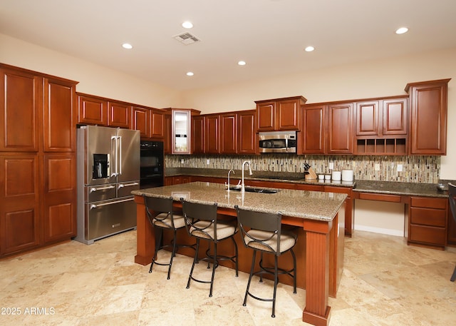 kitchen with tasteful backsplash, visible vents, an island with sink, appliances with stainless steel finishes, and a sink