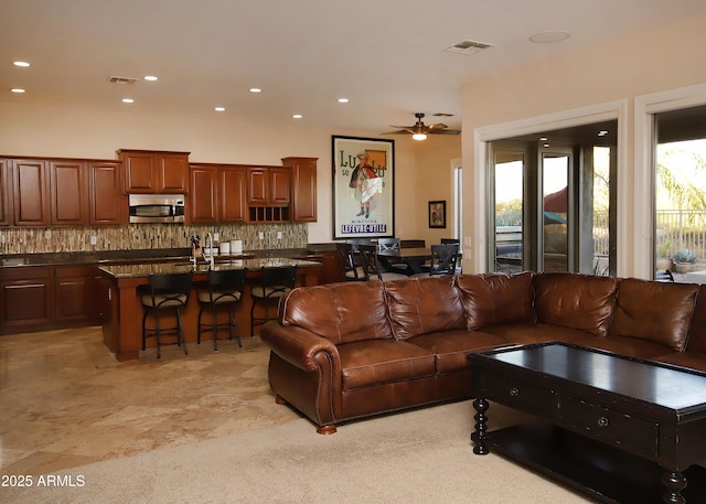 living room with a ceiling fan, visible vents, and recessed lighting