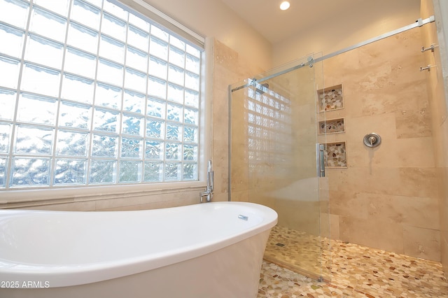 bathroom with a soaking tub and a shower stall