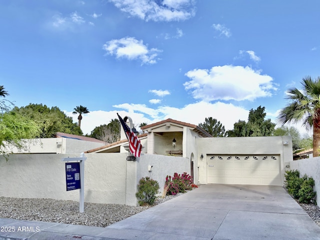 view of front of house featuring a fenced front yard, stucco siding, driveway, an attached garage, and a gate