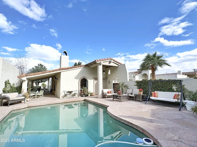 rear view of house with a fenced in pool, a tiled roof, a chimney, outdoor lounge area, and a patio