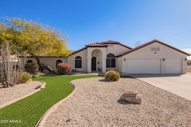 mediterranean / spanish-style home featuring an attached garage, a tile roof, concrete driveway, and stucco siding