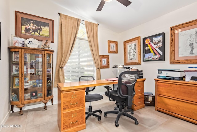 office space with a ceiling fan, vaulted ceiling, baseboards, and light tile patterned floors