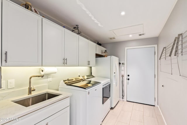 clothes washing area featuring washing machine and dryer, cabinet space, a sink, and visible vents