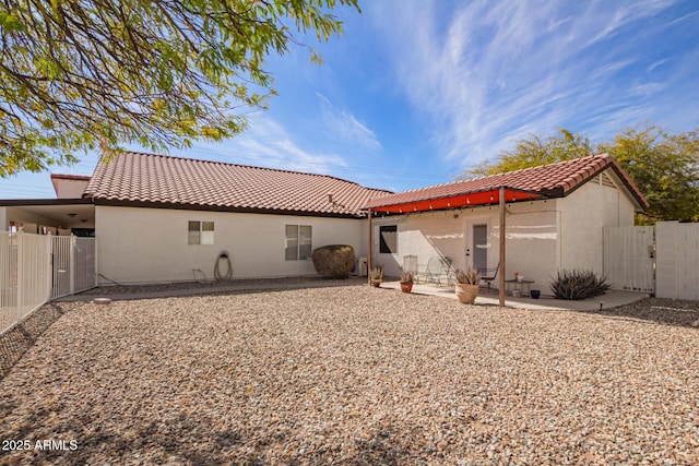 back of house with a patio, a tile roof, a gate, fence, and stucco siding