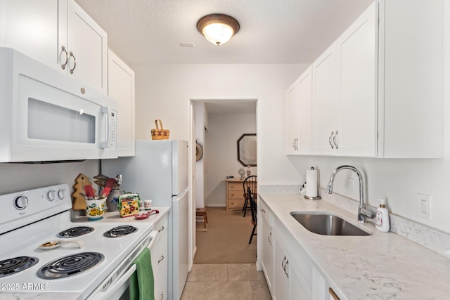 kitchen with white appliances, light tile patterned floors, light stone counters, white cabinetry, and a sink