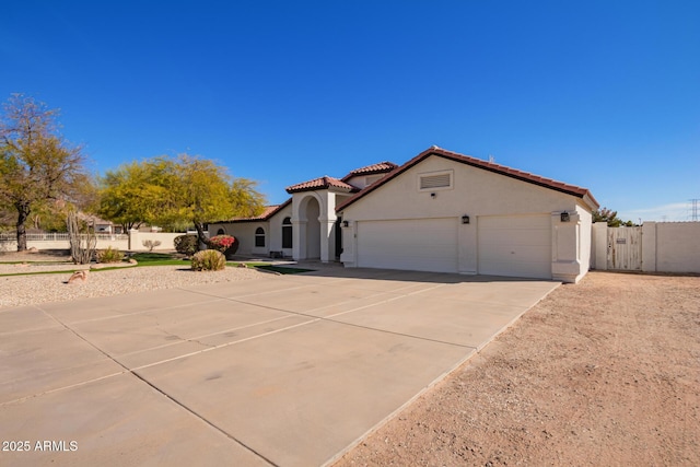 mediterranean / spanish-style house with driveway, a tile roof, an attached garage, fence, and stucco siding