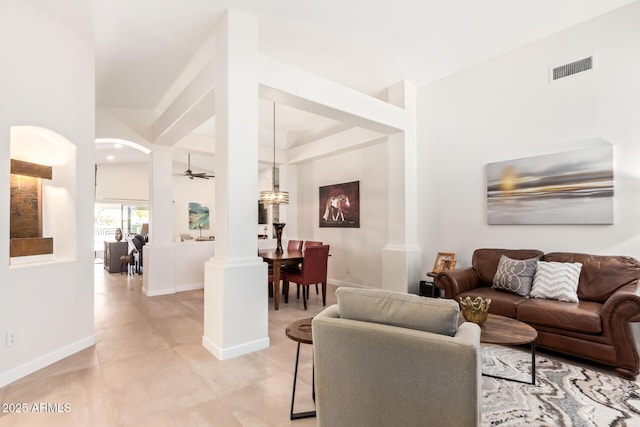 living area with light tile patterned flooring, visible vents, a ceiling fan, baseboards, and decorative columns