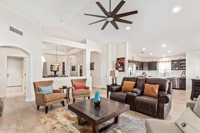 living room featuring arched walkways, lofted ceiling, recessed lighting, visible vents, and baseboards