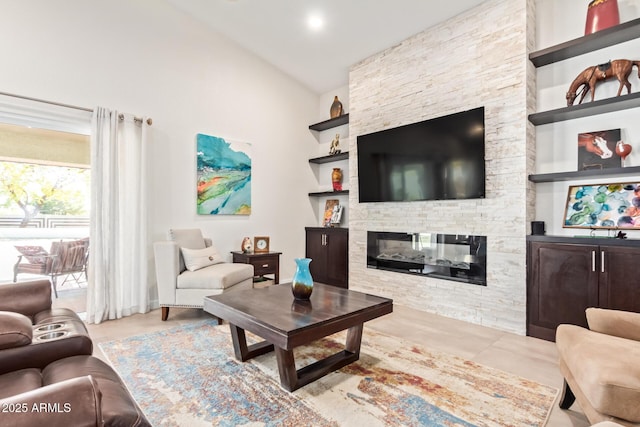 living area featuring built in shelves, vaulted ceiling, and a stone fireplace