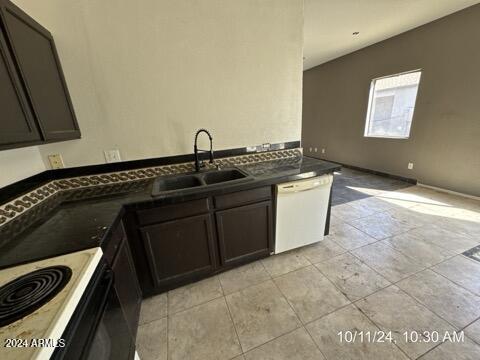 kitchen with kitchen peninsula, dark brown cabinets, sink, and white appliances