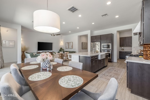 dining room with ceiling fan, sink, and light hardwood / wood-style floors