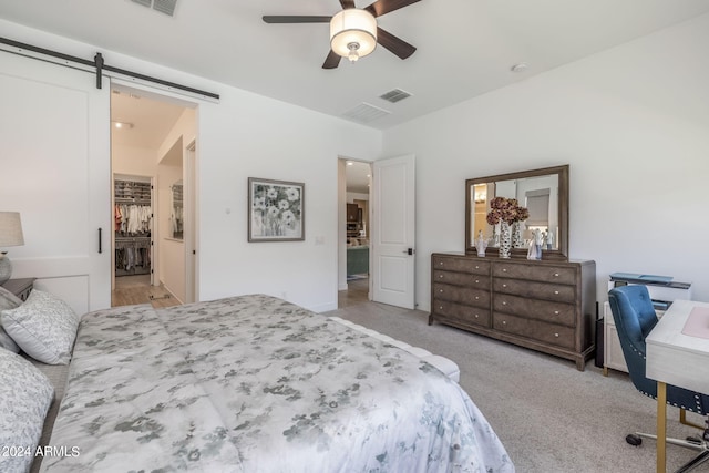 bedroom with a barn door, ceiling fan, and light colored carpet