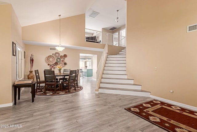 dining room with light hardwood / wood-style floors and high vaulted ceiling