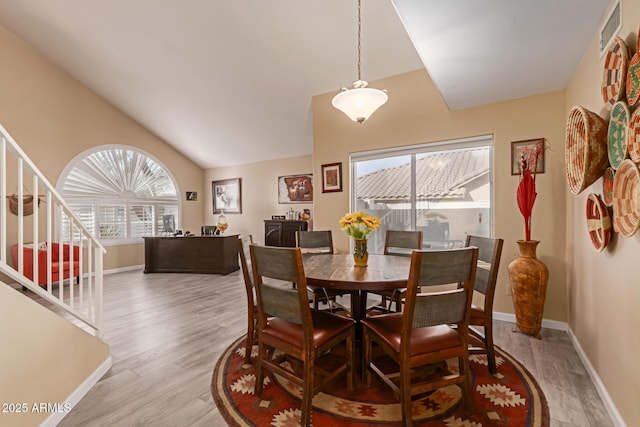 dining space featuring lofted ceiling, light hardwood / wood-style flooring, and a healthy amount of sunlight