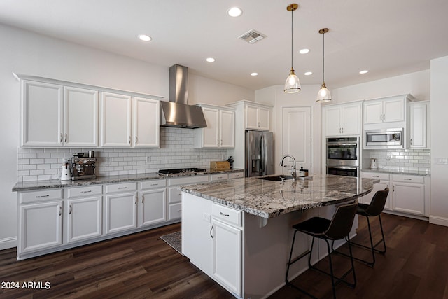 kitchen featuring decorative light fixtures, dark hardwood / wood-style flooring, appliances with stainless steel finishes, white cabinets, and wall chimney exhaust hood