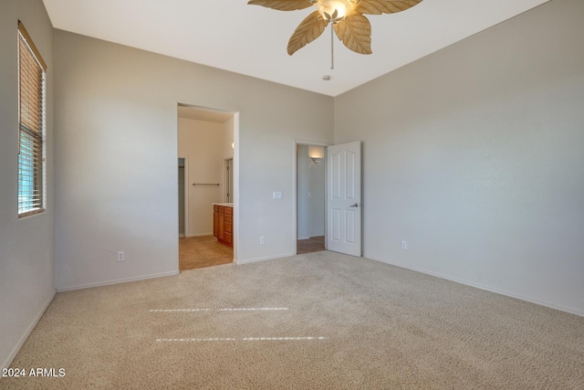 unfurnished bedroom featuring ceiling fan, ensuite bathroom, and light colored carpet