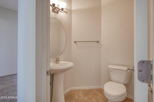 bathroom with toilet, sink, and tile patterned flooring