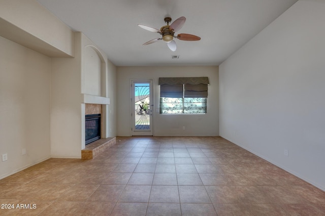 unfurnished living room featuring ceiling fan, light tile patterned flooring, and a fireplace