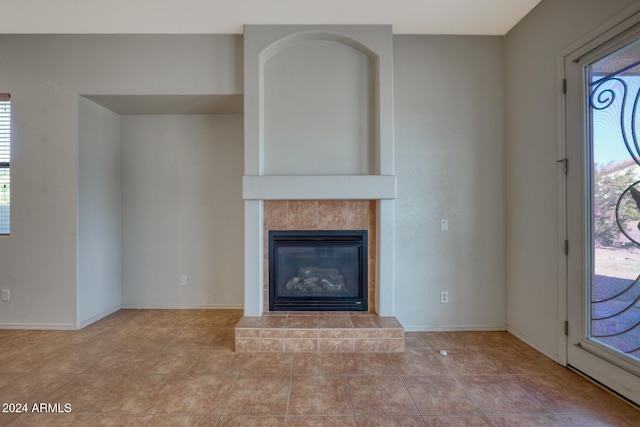 unfurnished living room featuring a tiled fireplace and light tile patterned floors