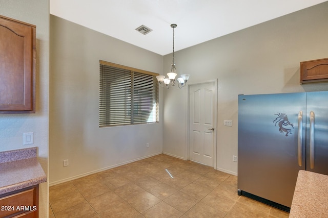 kitchen featuring light tile patterned floors, stainless steel refrigerator, a chandelier, and pendant lighting