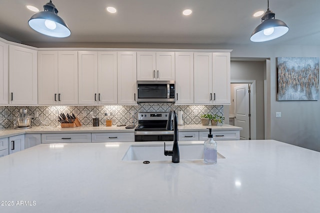 kitchen featuring decorative light fixtures, backsplash, sink, white cabinetry, and stainless steel appliances