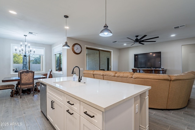 kitchen featuring an island with sink, dishwasher, pendant lighting, white cabinets, and sink