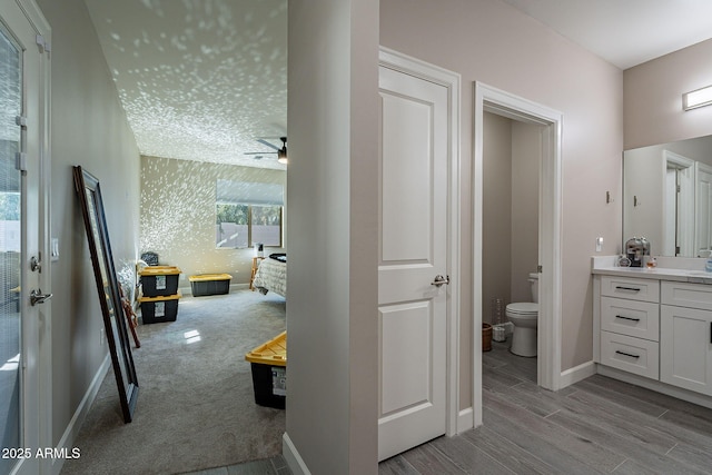 bathroom with toilet, vanity, ceiling fan, and wood-type flooring