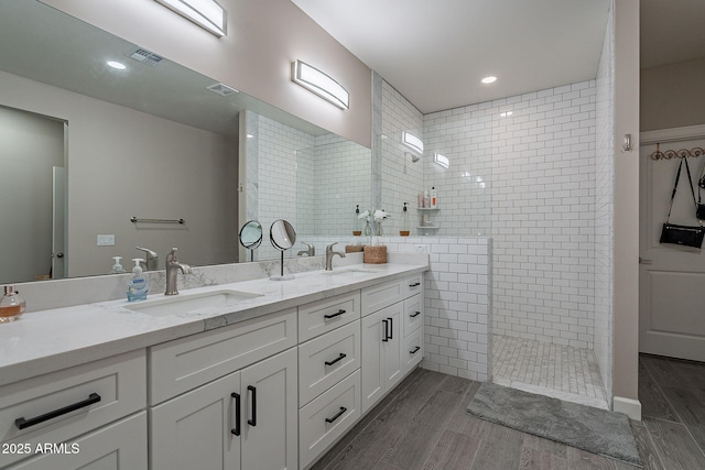 bathroom featuring a tile shower, vanity, and tile walls