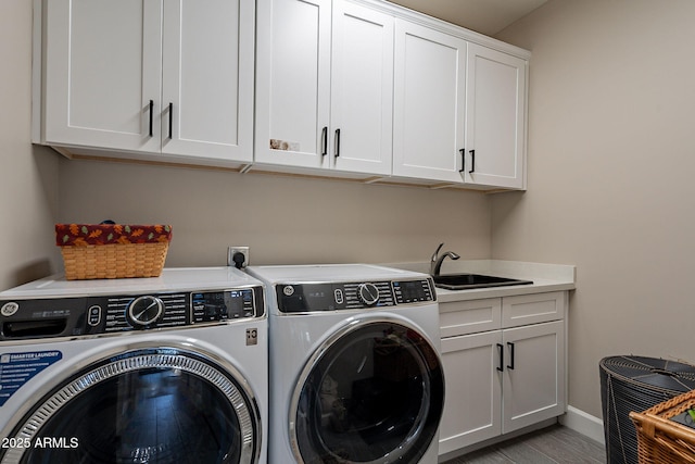 clothes washing area featuring cabinets, light hardwood / wood-style flooring, sink, and washing machine and dryer