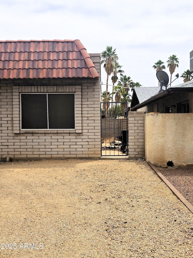 18227 N 40th Pl, Phoenix, AZ 85032 - view of property exterior featuring brick siding, a tiled roof, a gate, fence, and mansard roof
