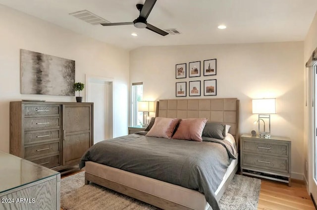 bedroom featuring ceiling fan, light hardwood / wood-style floors, and lofted ceiling